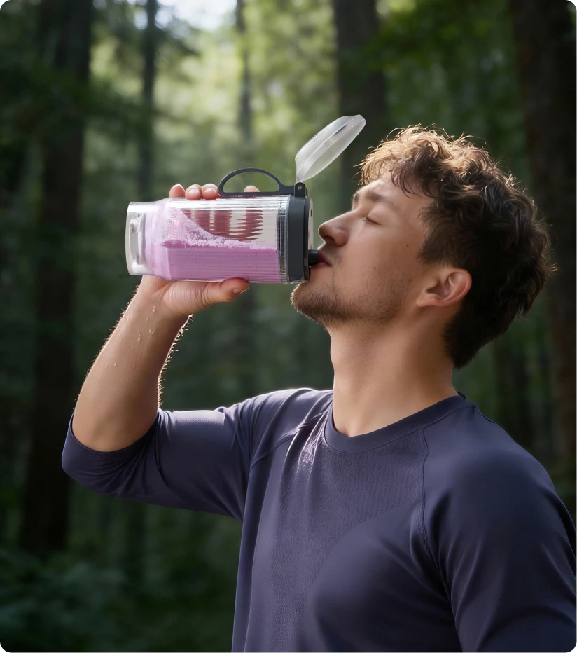 Usuario bebiendo un batido del vaso portátil Dreame Portable Blender durante una caminata por el bosque