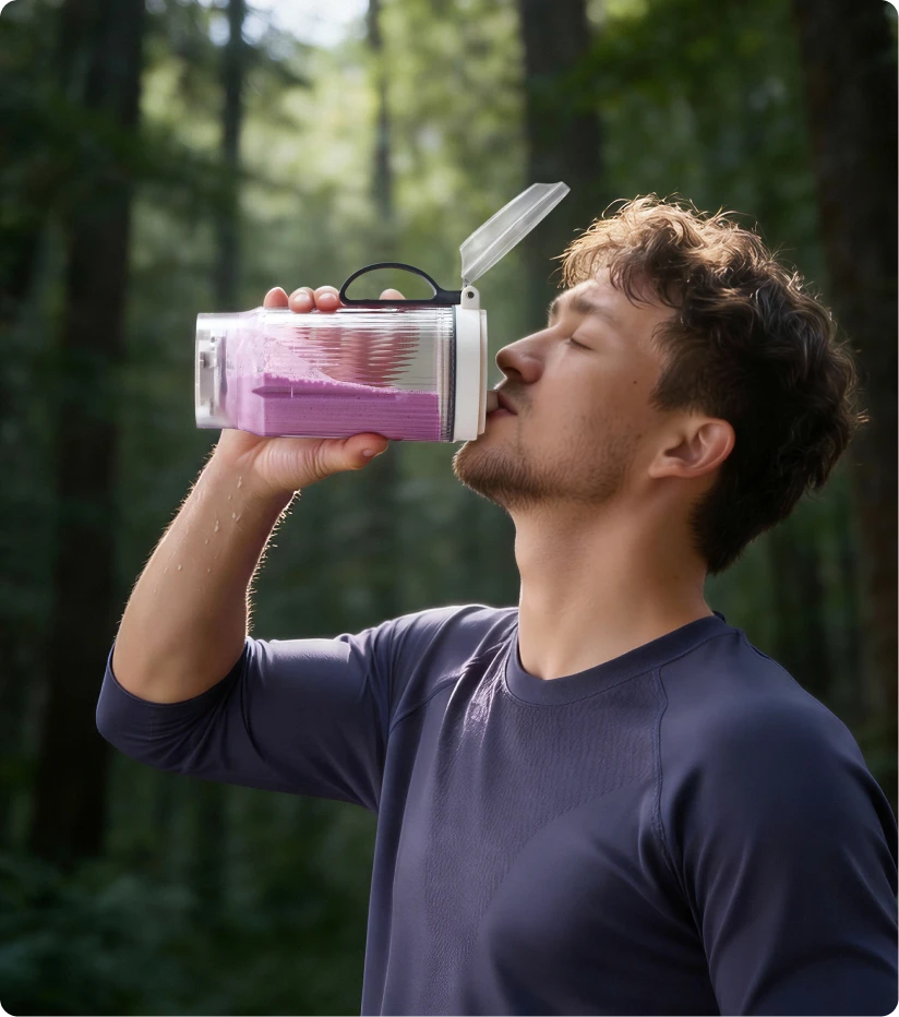 Usuario bebiendo un batido del vaso portátil Dreame Portable Blender durante una caminata por el bosque
