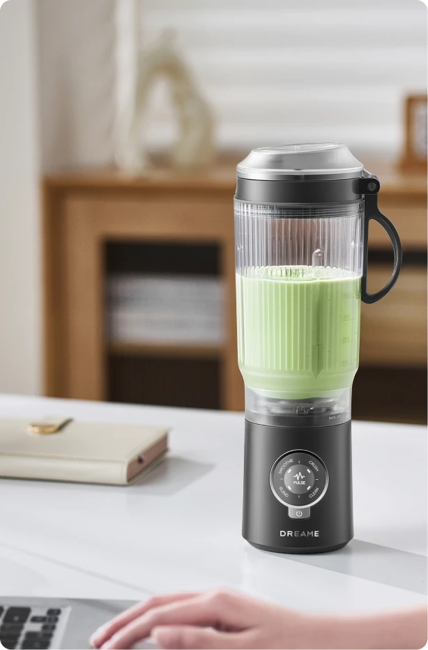 Batidora Dreame Portable Blender diseño sin cables en un escritorio de oficina preparando una bebida verde
