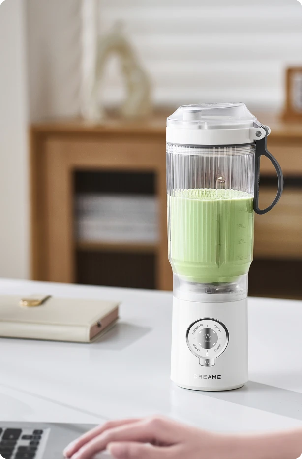 Batidora Dreame Portable Blender diseño sin cables en un escritorio de oficina preparando una bebida verde