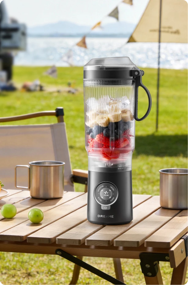 Batidora Dreame Portable Blender diseño sin cables en mesa de picnic preparando bebidas de frutas al aire libre