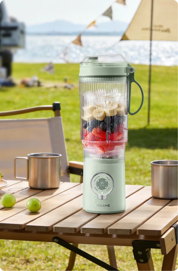 Batidora Dreame Portable Blender diseño sin cables en mesa de picnic preparando bebidas de frutas al aire libre